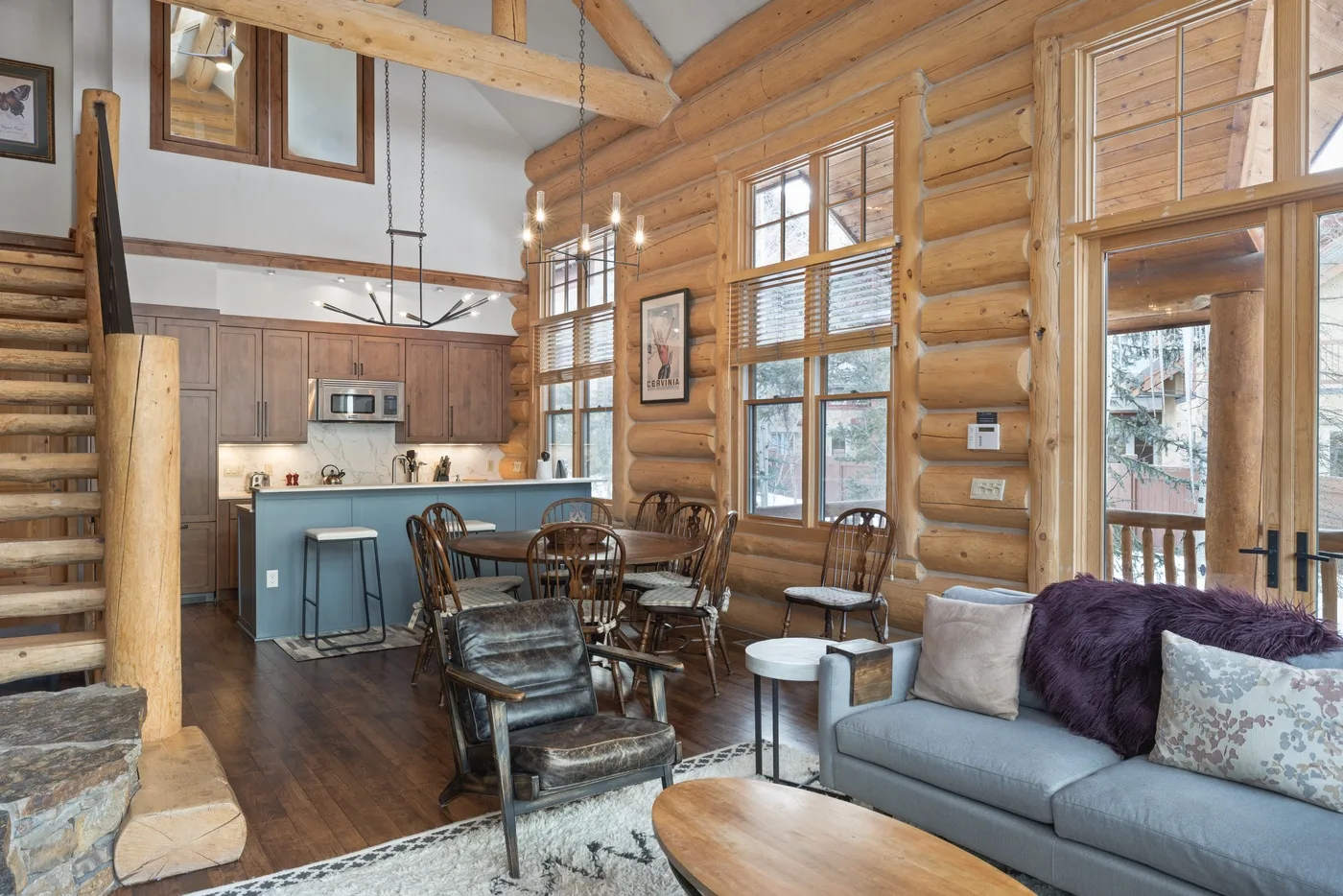 A log cabin living room and dining area with large windows and seating.