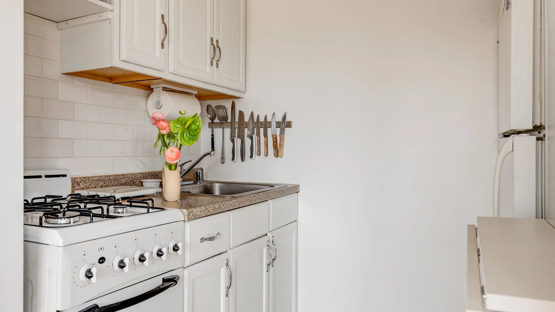 Una cocina luminosa con gabinetes blancos, una encimera y una estufa de gas.