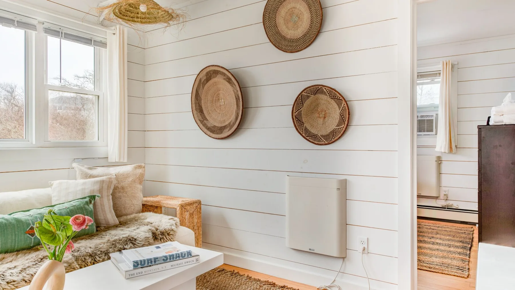 Una sala luminosa con una ventana, asientos acolchados y decoración tejida en la pared.