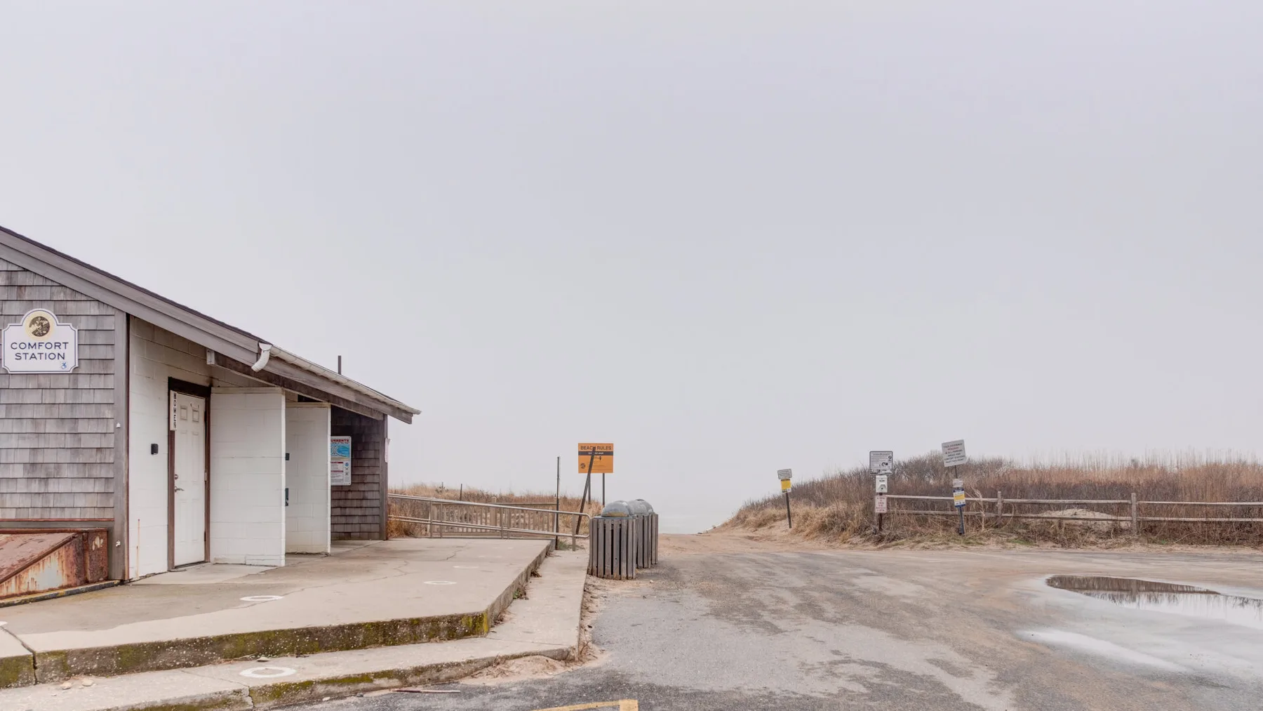 Un pequeño edificio junto a la carretera está junto a un espacio abierto de arena.