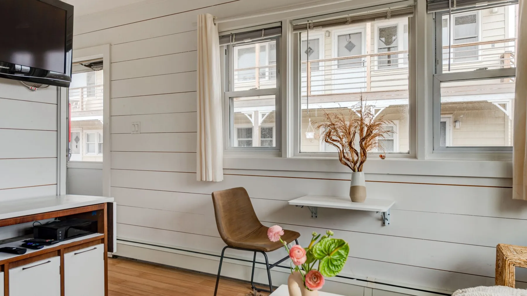 Una sala luminosa con ventanas grandes y una pequeña zona para sentarse.