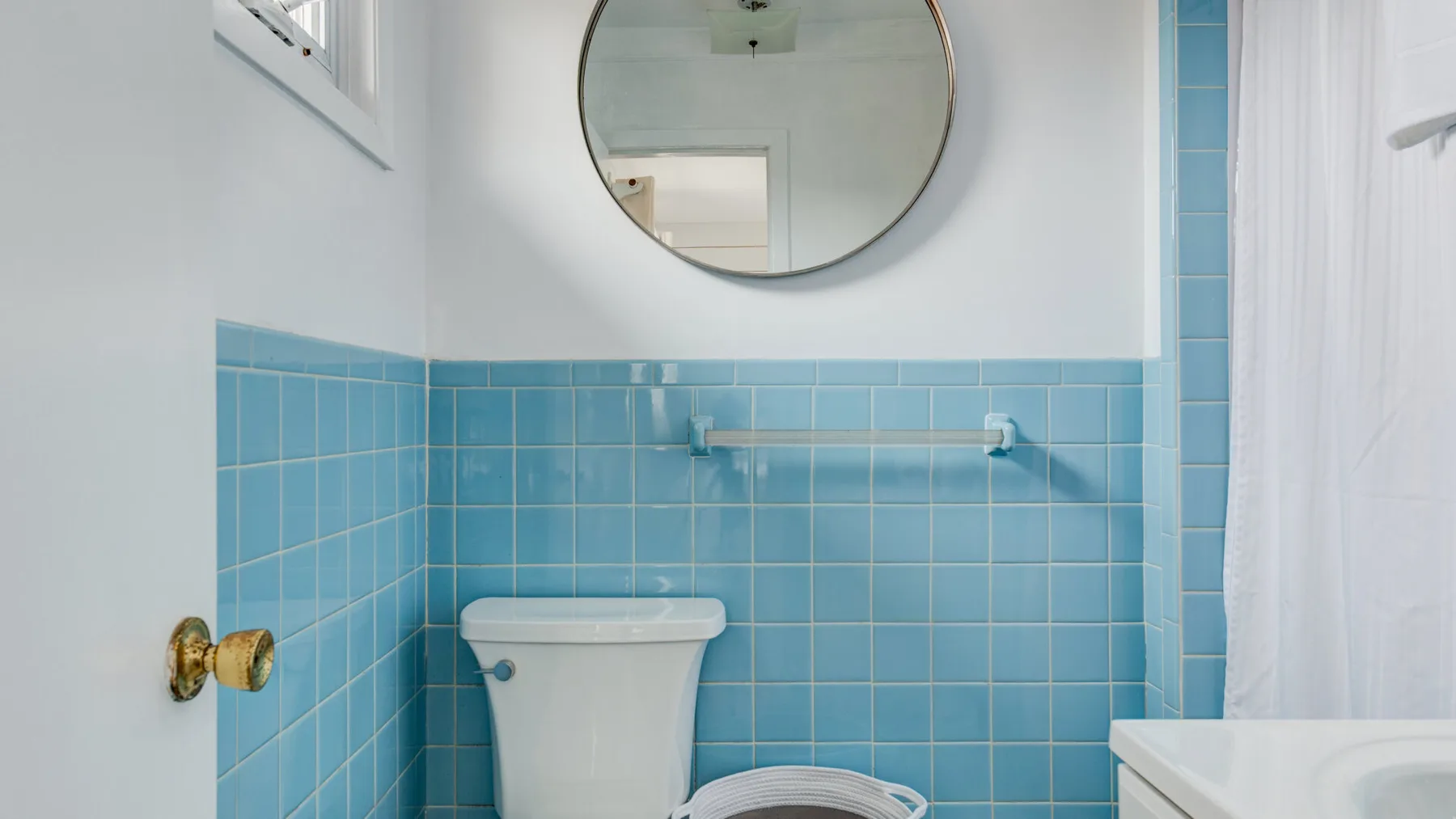 Un baño con paredes de azulejos azules, un inodoro y una cortina de ducha.
