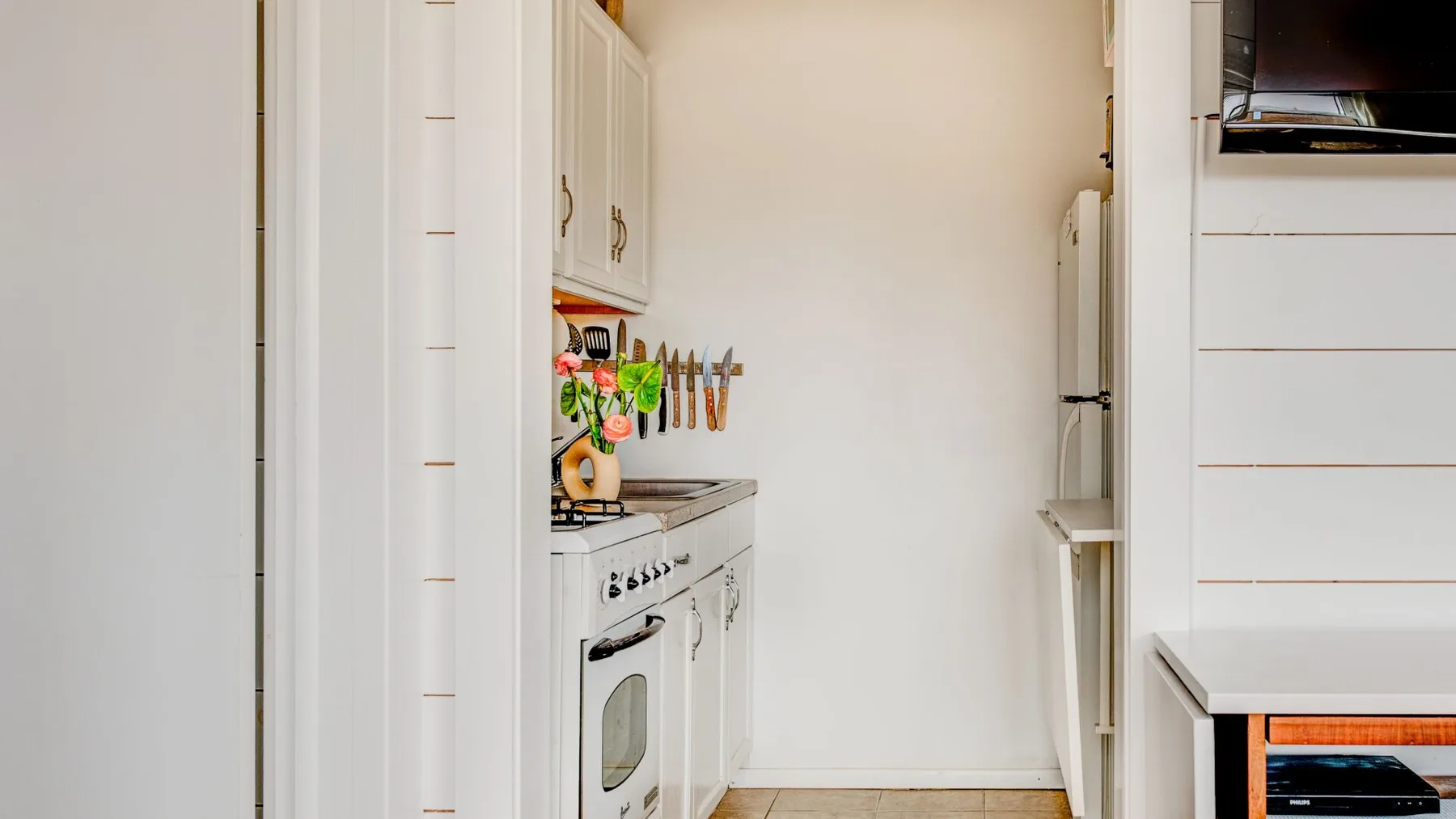 Una cocina estrecha con gabinetes blancos, una encimera y un horno empotrado.