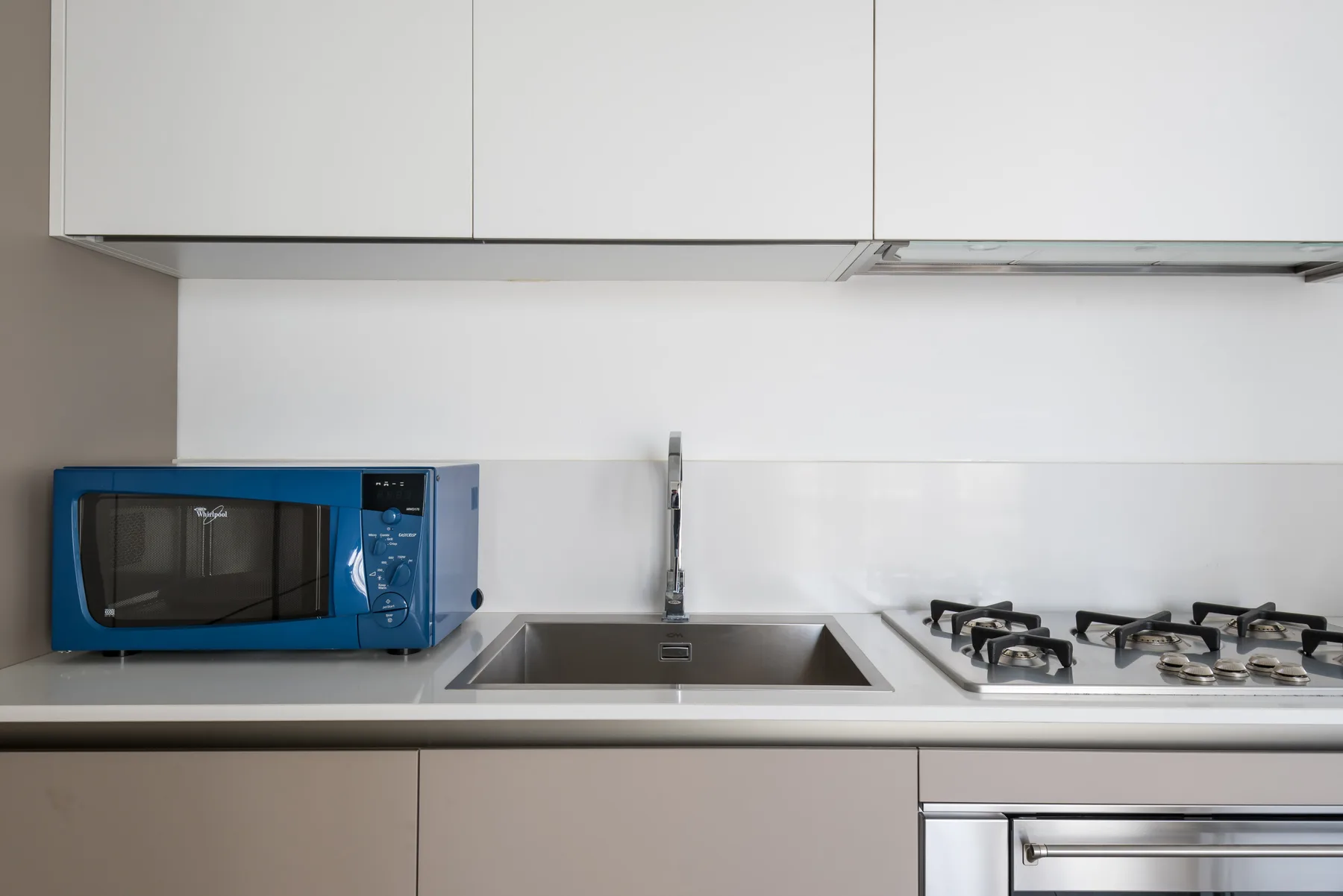 A modern kitchen with a microwave, sink, and stovetop along the counter.