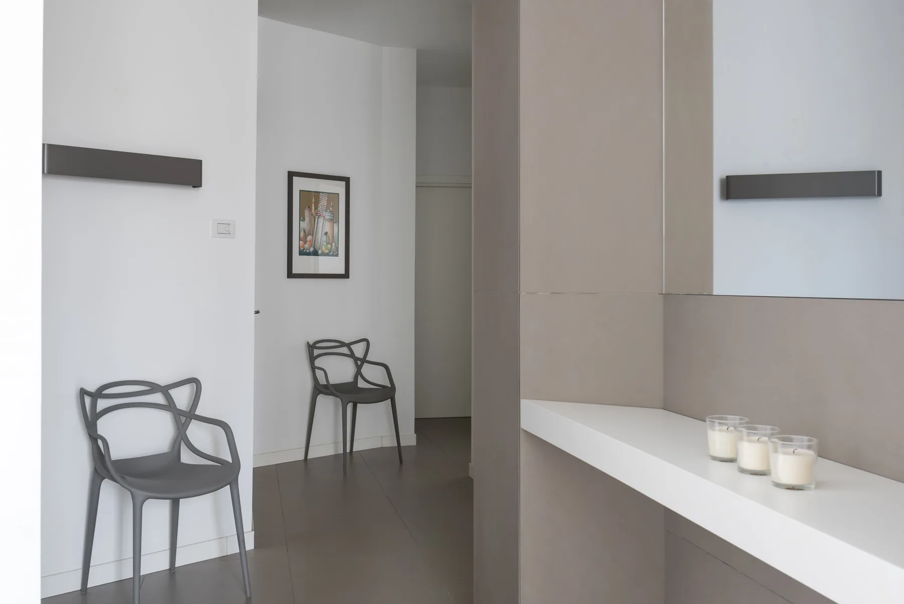 A modern interior hallway with seating and a white counter holding candles.