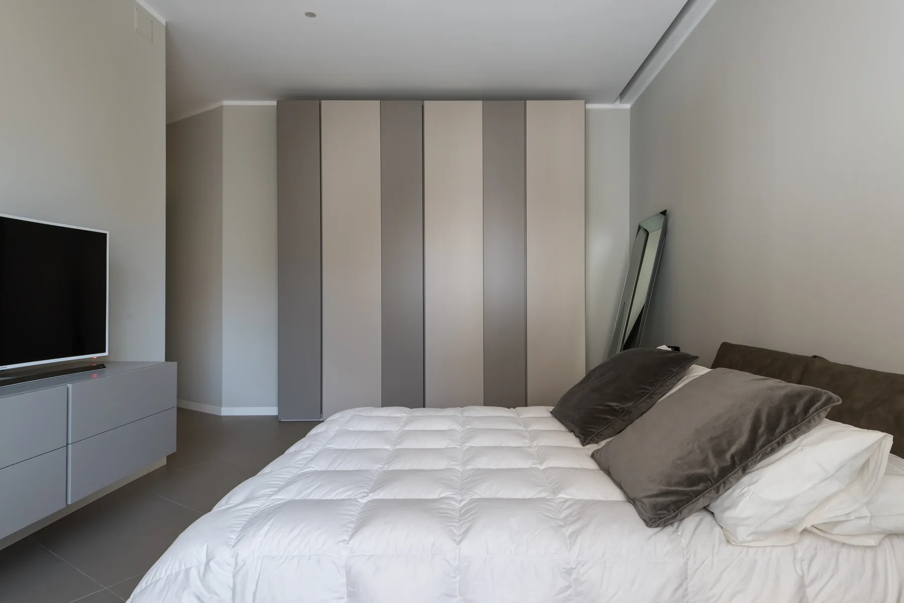 A bedroom with a bed, wardrobe, and television.