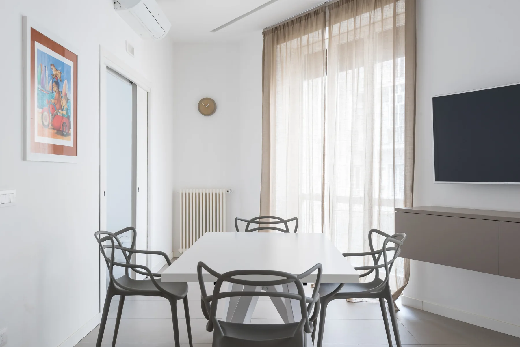 A bright dining area with a table, chairs, and a large curtained window.