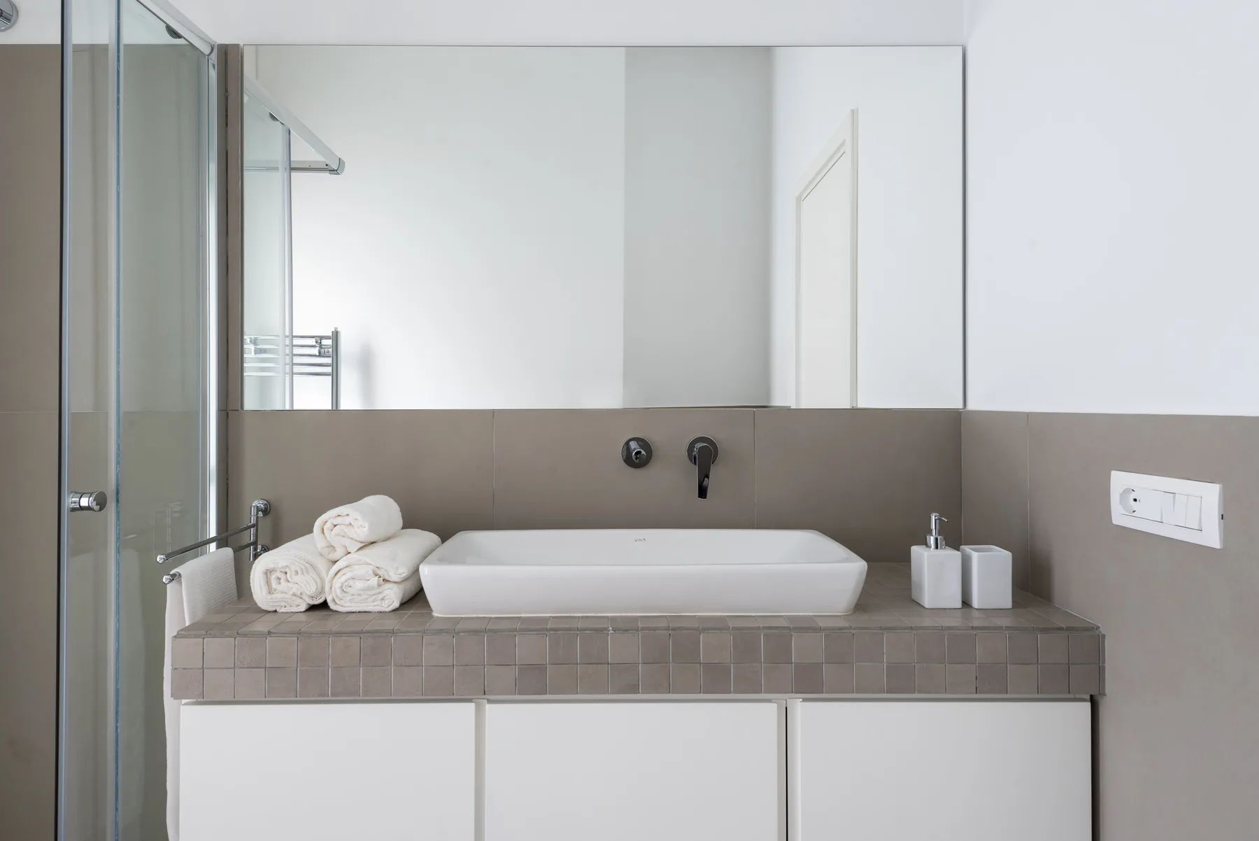 A bathroom vanity with a vessel sink, folded towels, and a large wall mirror.