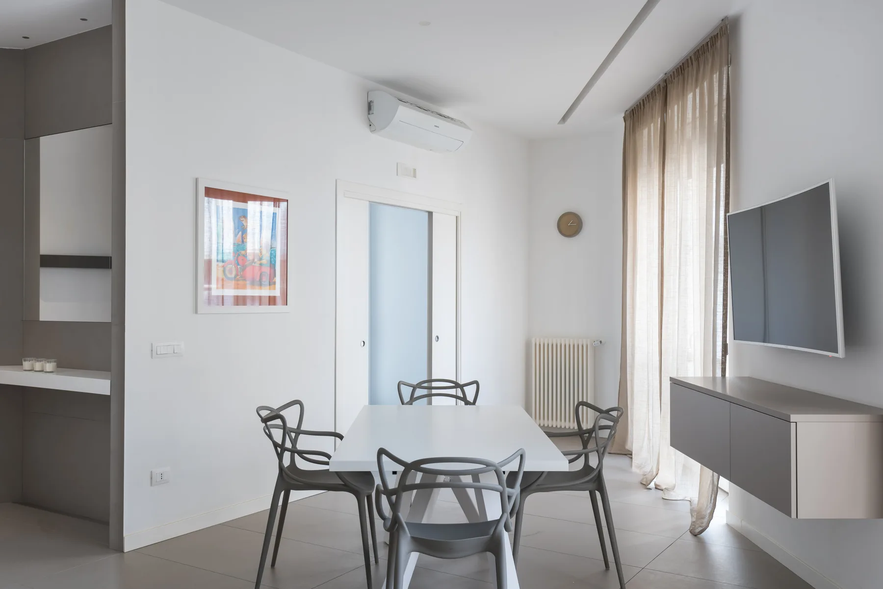 A bright dining area with a table and chairs beside tall curtained windows.