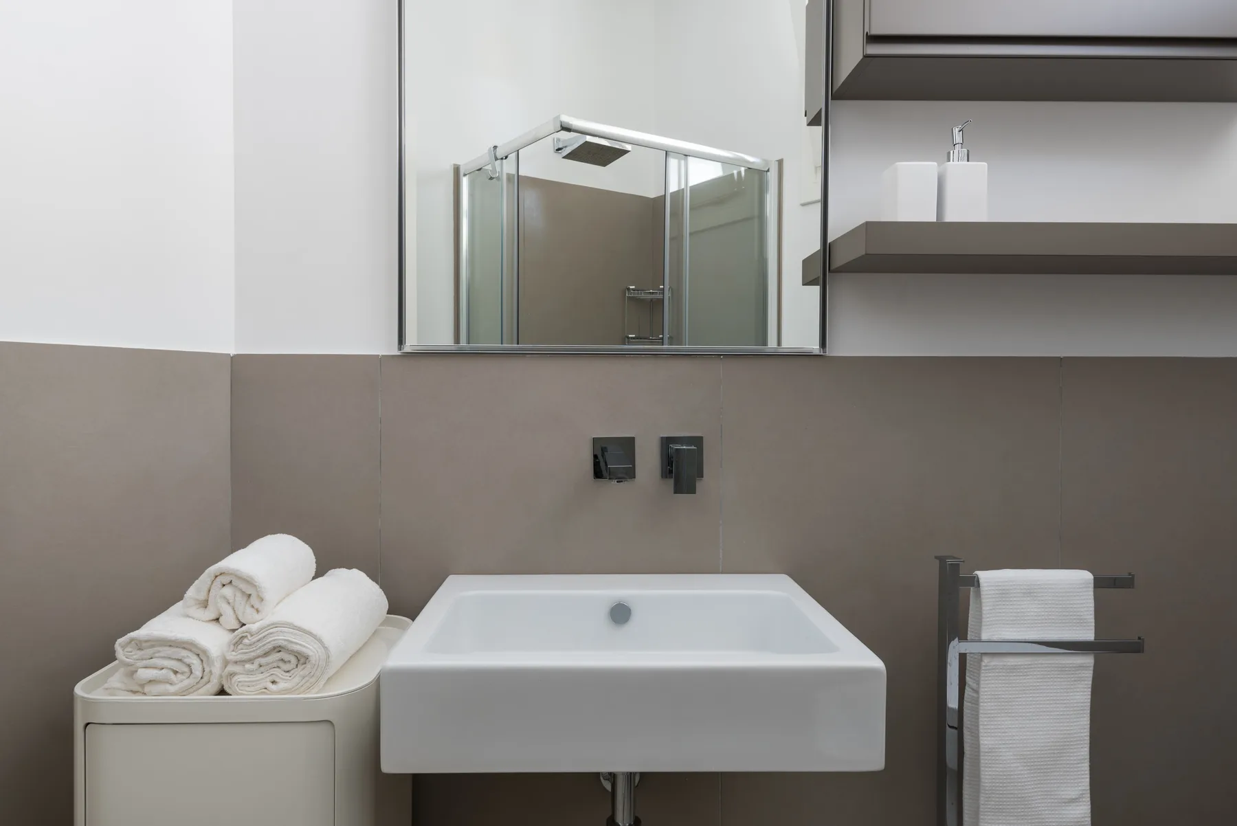 A modern bathroom with a white sink and glass shower.