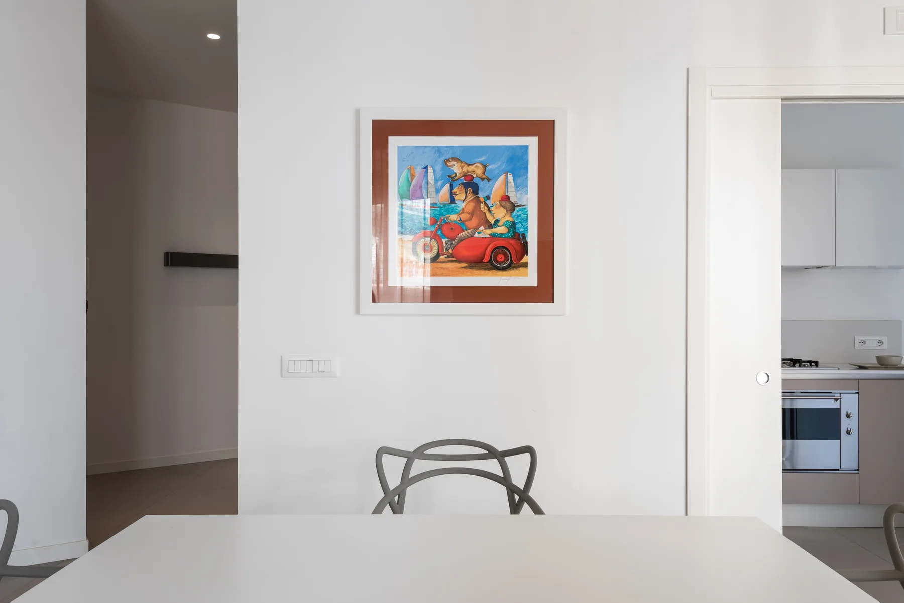 A bright dining area with a table, chairs, and colorful framed artwork.