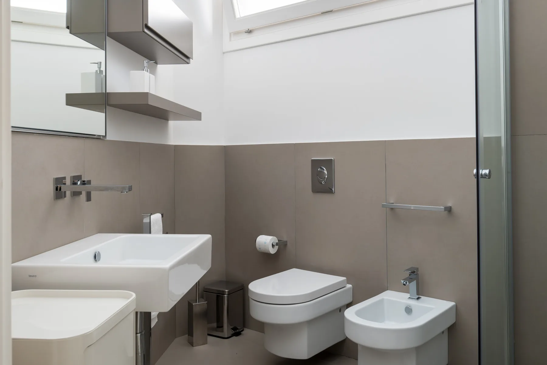 A modern bathroom with a sink, toilet, and bidet.