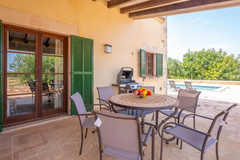 Una zona de comedor al aire libre con una mesa redonda y asientos junto a una piscina.