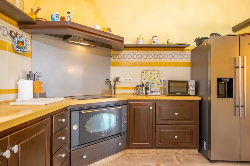 Una cocina con gabinetes marrones, un horno sobre la encimera y un refrigerador de acero inoxidable.