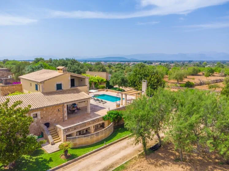 Una casa de campo y una piscina están rodeadas de árboles y campos abiertos.