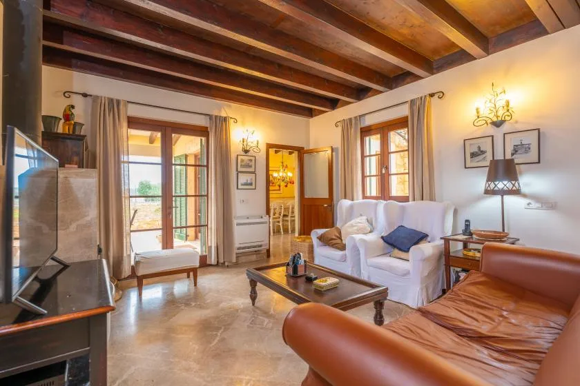 Una sala de estar con asientos, una mesa de centro y vigas de madera a la vista.