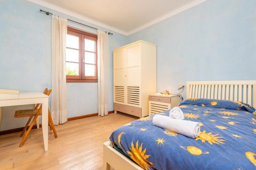 Un dormitorio con una colcha azul, un armario y una ventana.