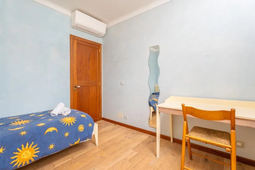 Un dormitorio con una colcha azul estampada y un escritorio pequeño.