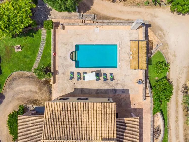 Vista aérea de una piscina junto a un edificio con techo de tejas.