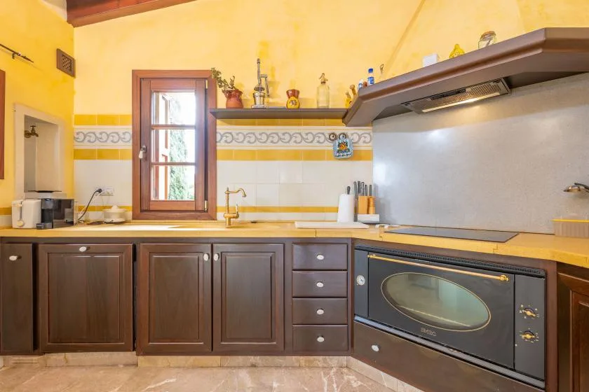 Una cocina con gabinetes oscuros, una encimera y un horno empotrado.