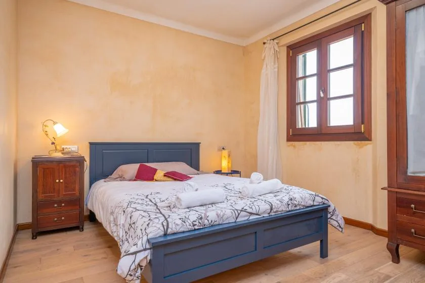 Un dormitorio con una cama bajo una ventana y paredes claras.