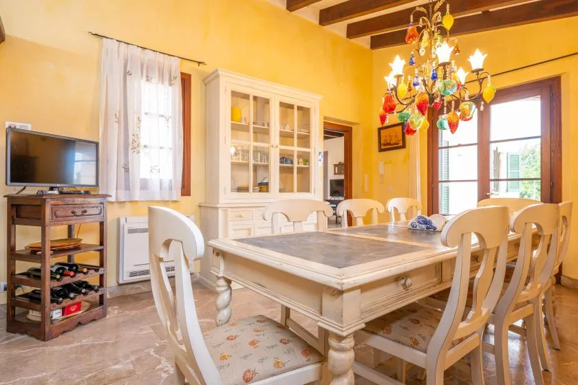 Comedor con una mesa grande y una lámpara de araña colorida.