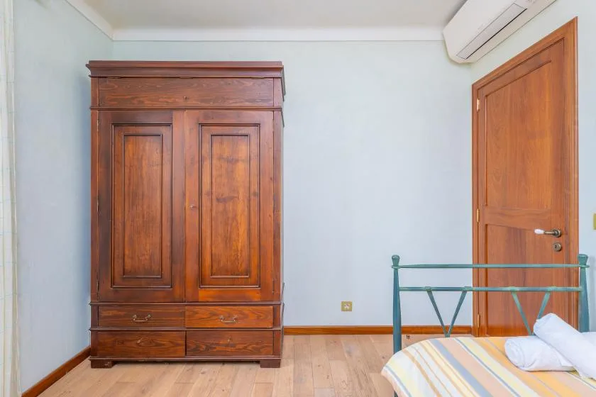 Un dormitorio con un armario de madera, una cama y una puerta de madera.