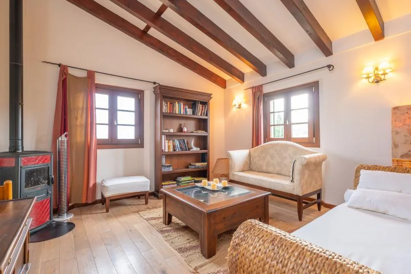Una sala luminosa con asientos, una mesa de centro de madera y vigas expuestas en el techo.
