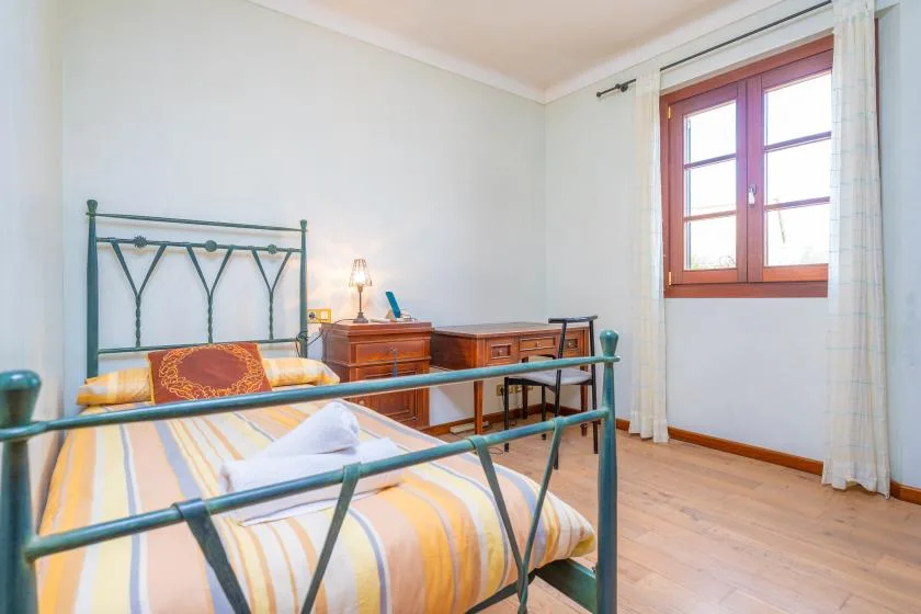 Un dormitorio con una cama de metal y muebles de madera junto a una ventana.