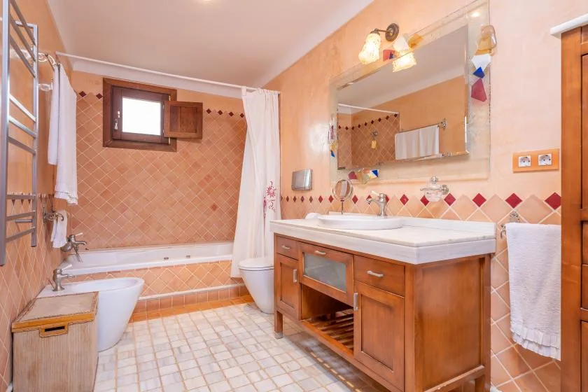 Un baño con azulejos, bañera, cortina de ducha y mueble de madera.