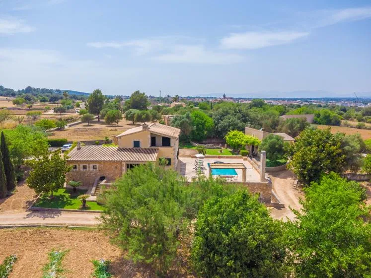 Vista aérea de una propiedad rural con piscina entre árboles y campos.
