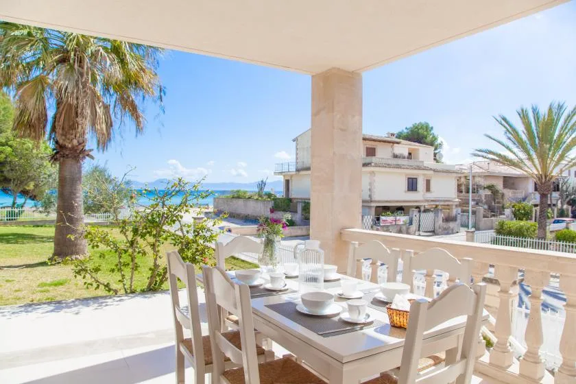 Una zona de comedor exterior cubierta da a un jardín y al mar.