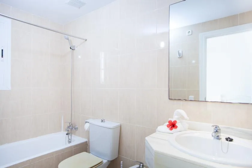 Un baño luminoso con bañera, inodoro y lavabo.