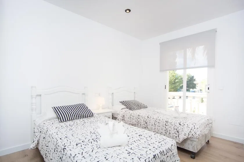 Un dormitorio luminoso con dos camas vestidas con ropa de cama estampada.