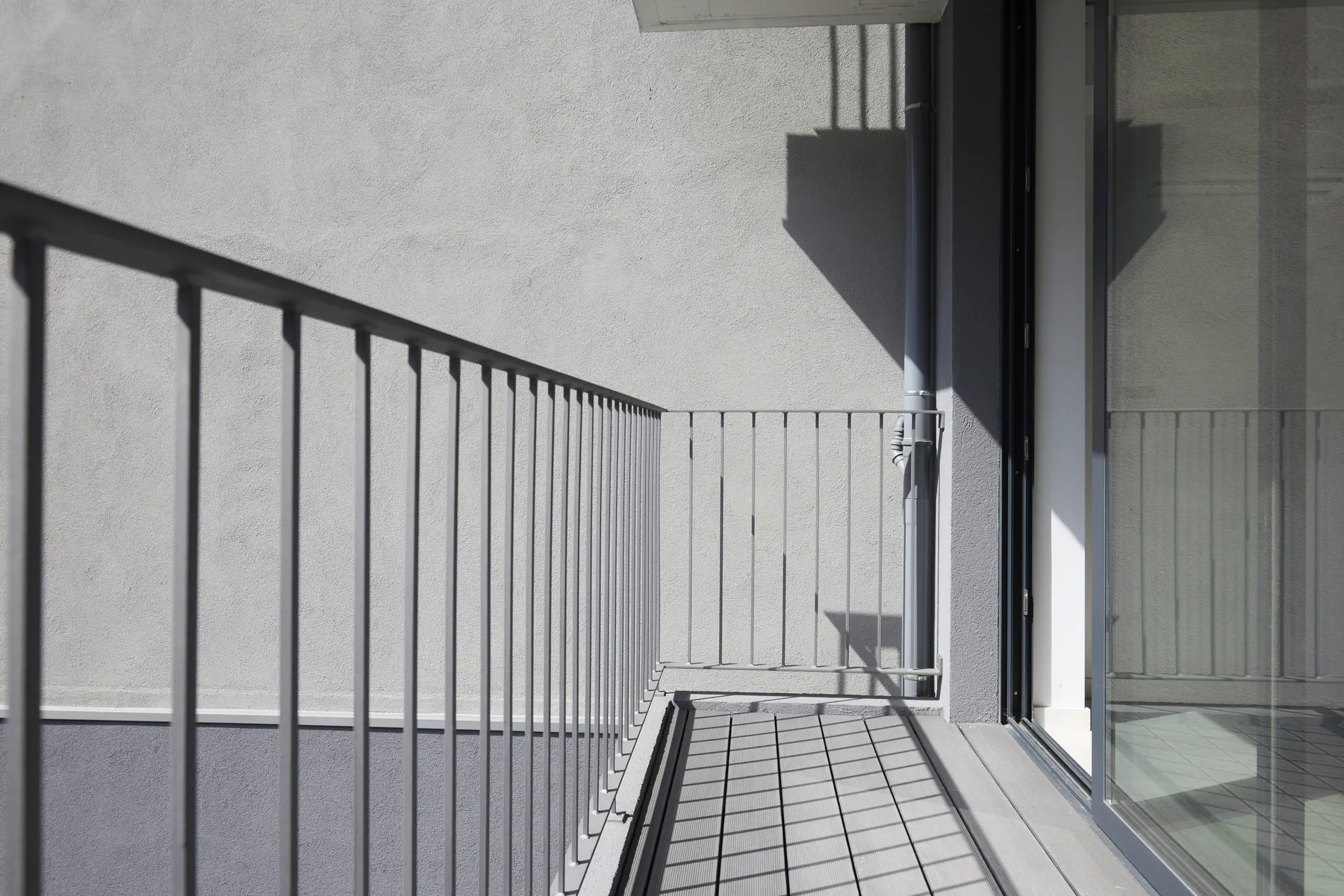 A narrow balcony with a metal railing beside a glass door.