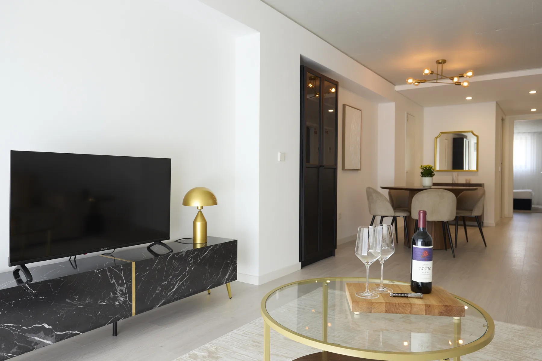 Una sala de estar y comedor con televisor, mesa y mesa de centro de vidrio.