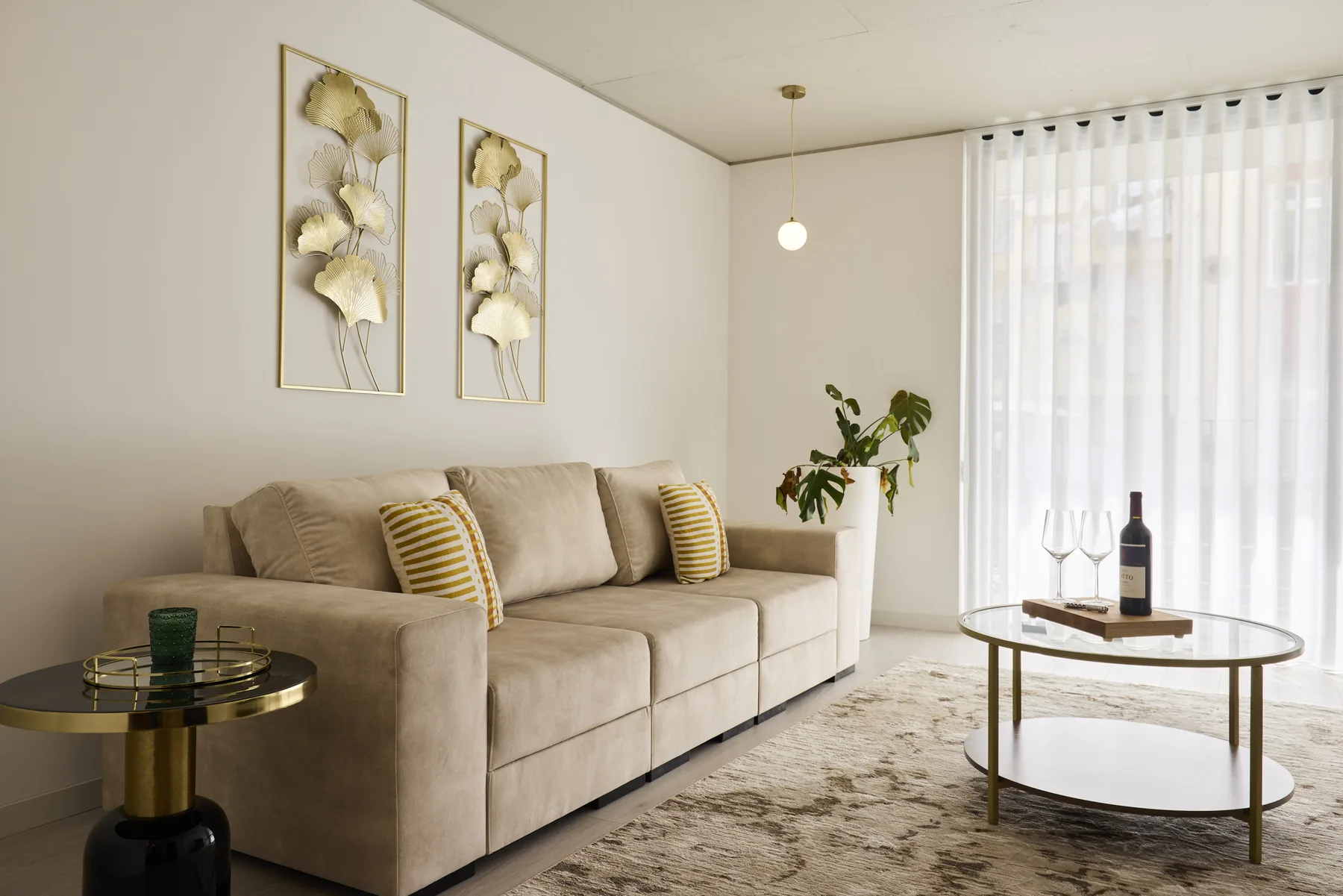 Una sala de estar con un sofá beige y cortinas translúcidas.