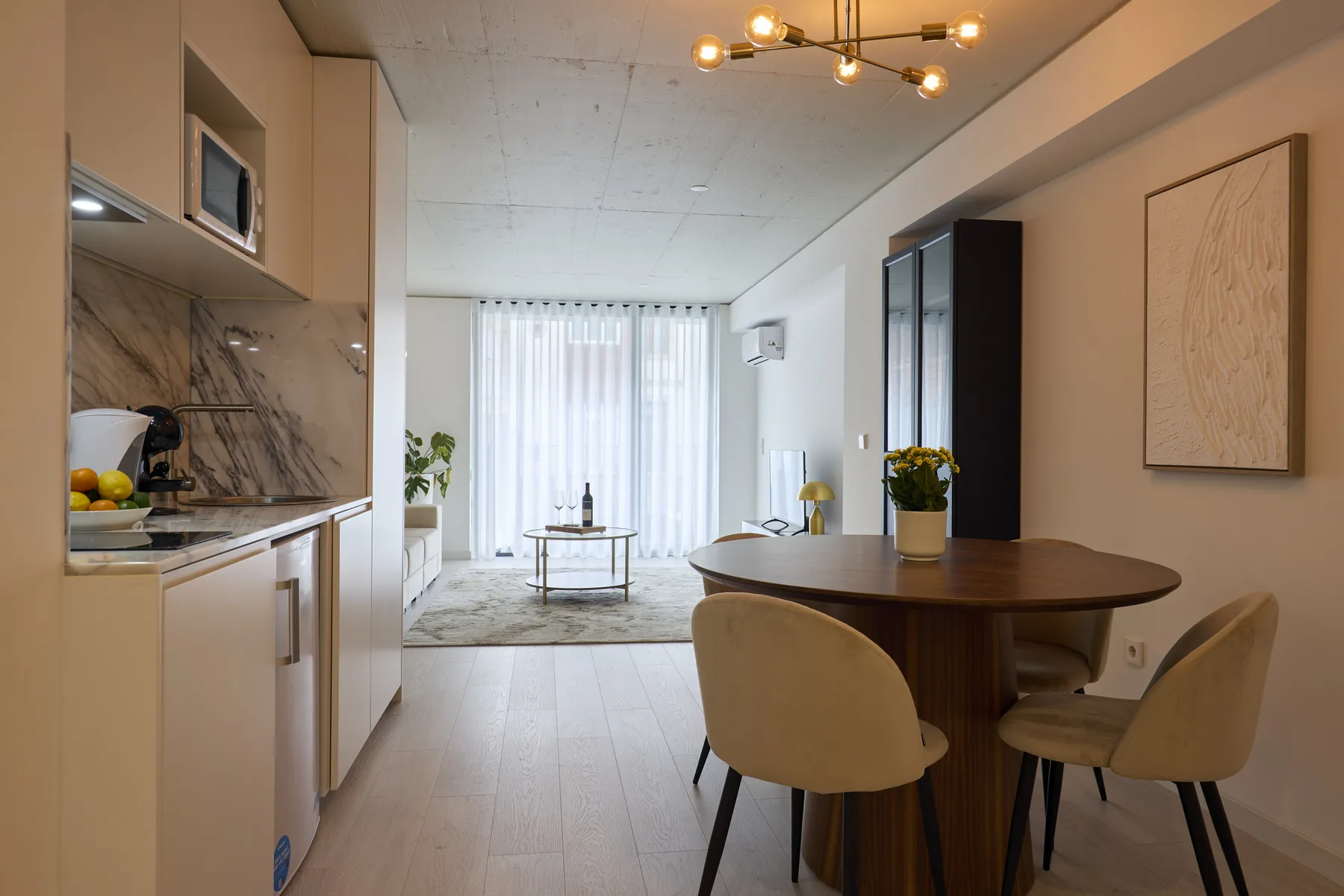 Cocina y comedor diáfanos con una mesa redonda y una luminosa zona de estar.