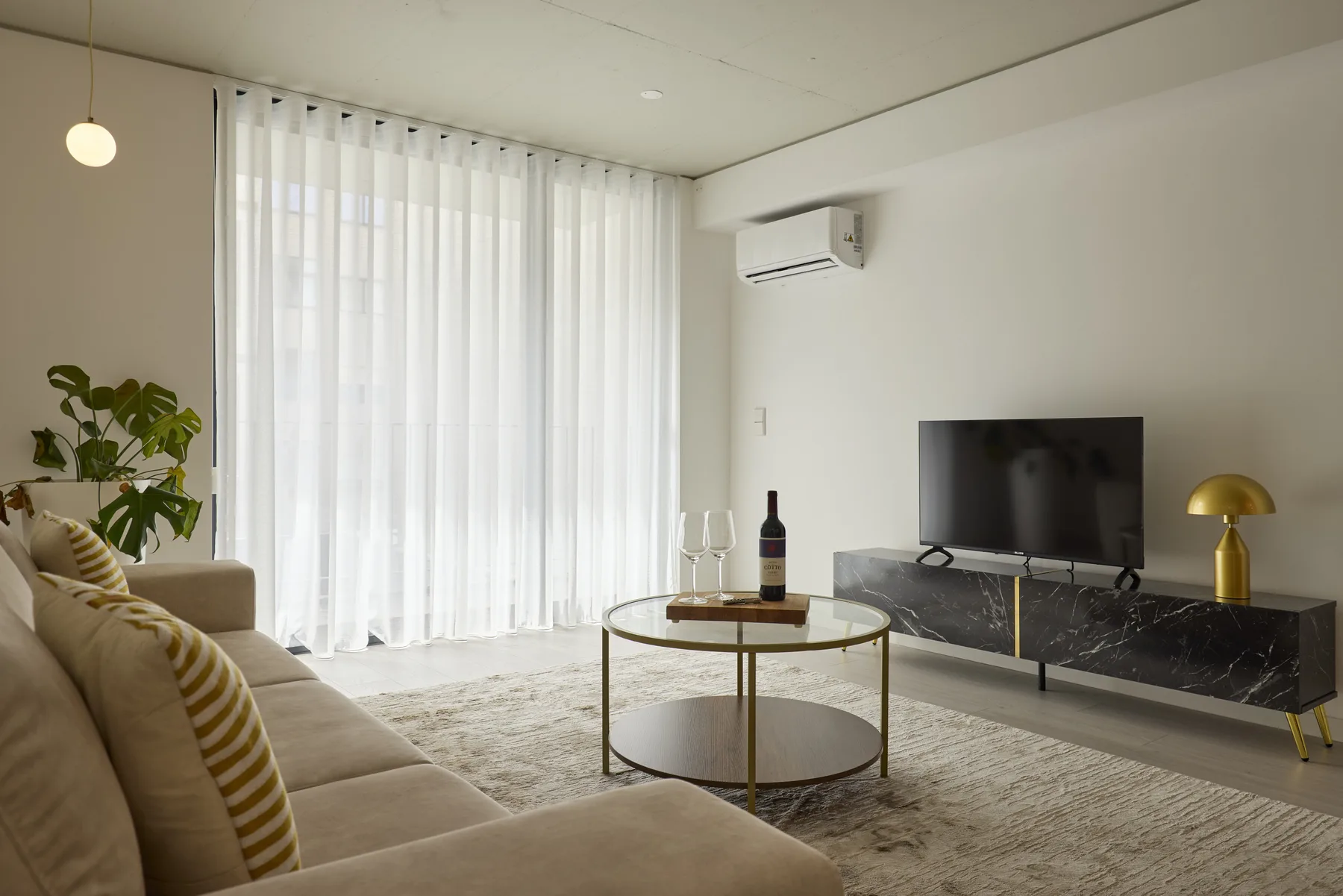 Una sala de estar luminosa con asientos, una mesa de centro redonda y un televisor.