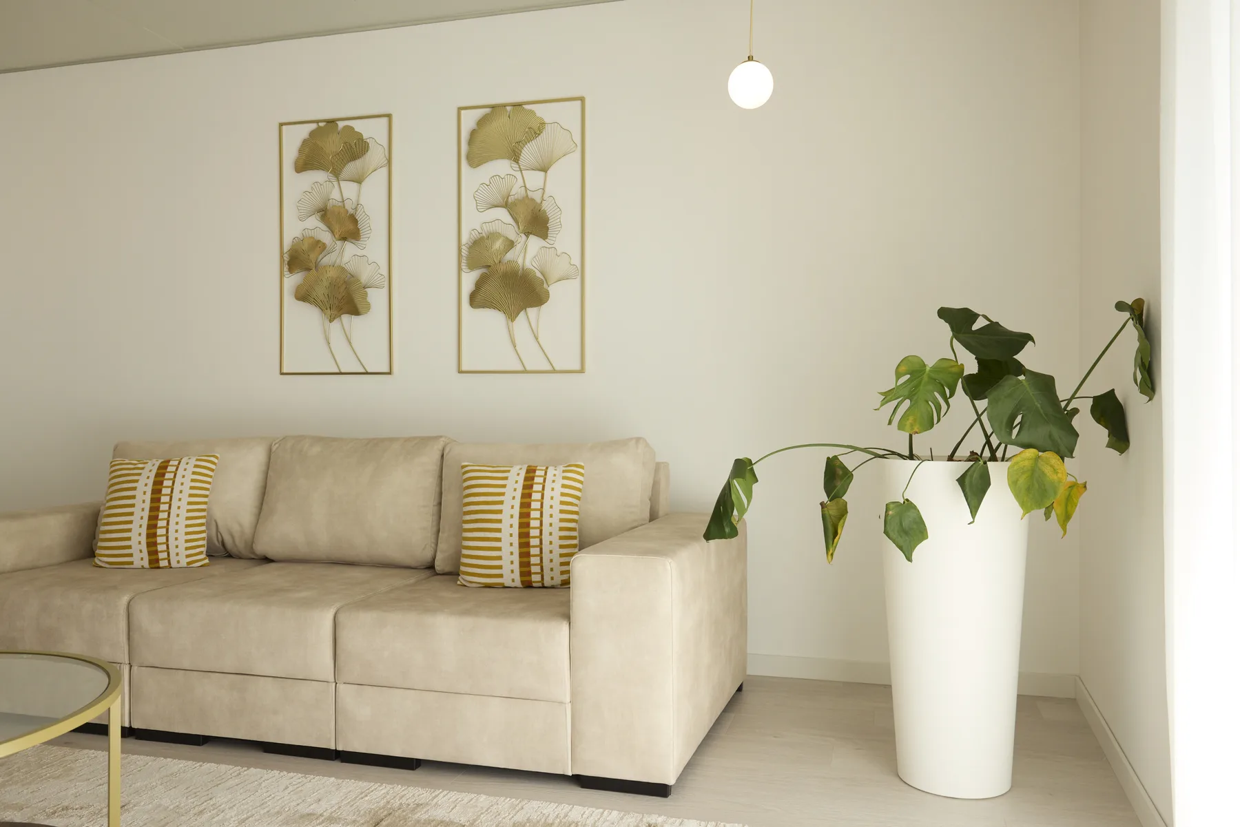 A living room with beige seating and a potted plant beside it.