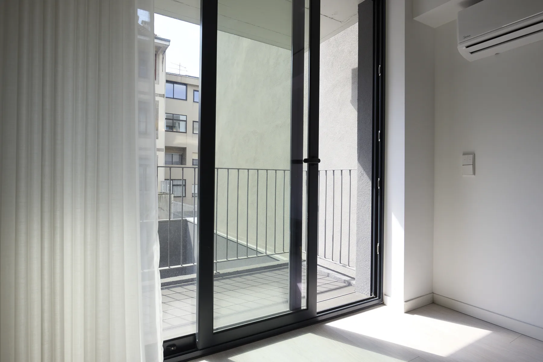 A bright room with sliding glass doors opening onto a balcony.