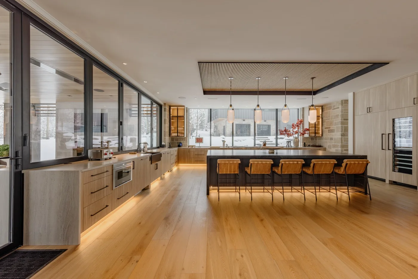 A spacious modern kitchen with a long island and warm wood flooring.