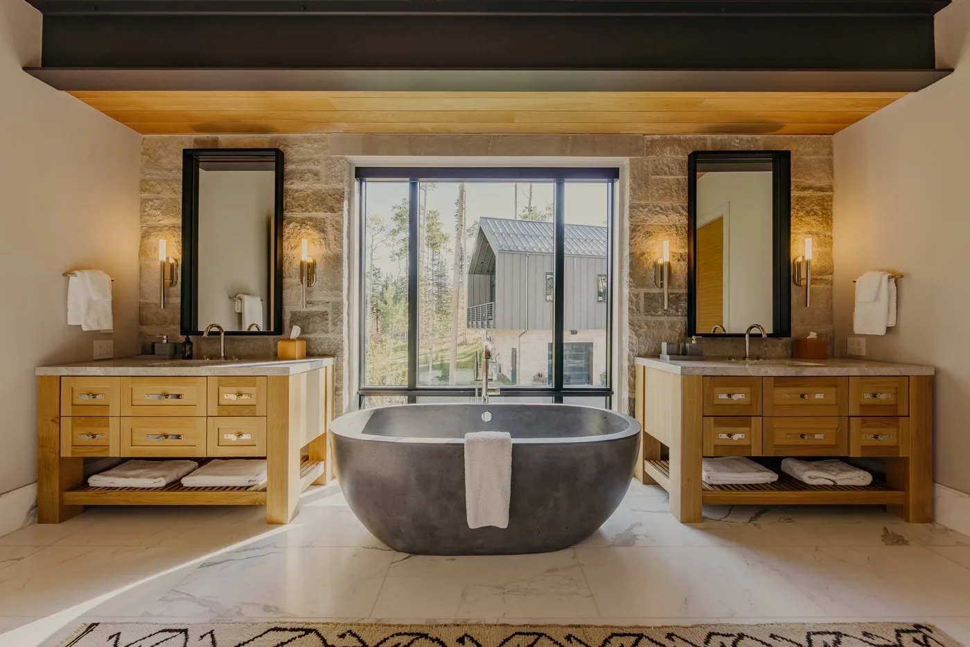 A bathroom with a freestanding bathtub centered between two vanity areas.
