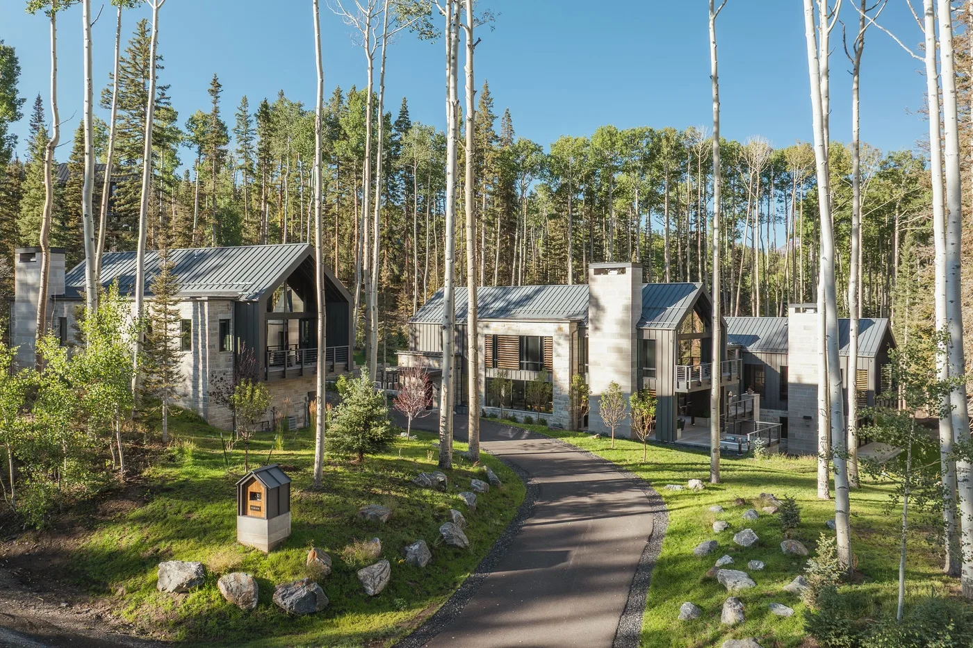 A paved path winds past modern cabins among tall trees.