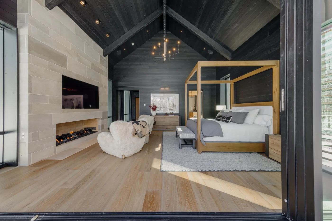 A spacious bedroom with a canopy bed, seating area, and high vaulted ceiling.