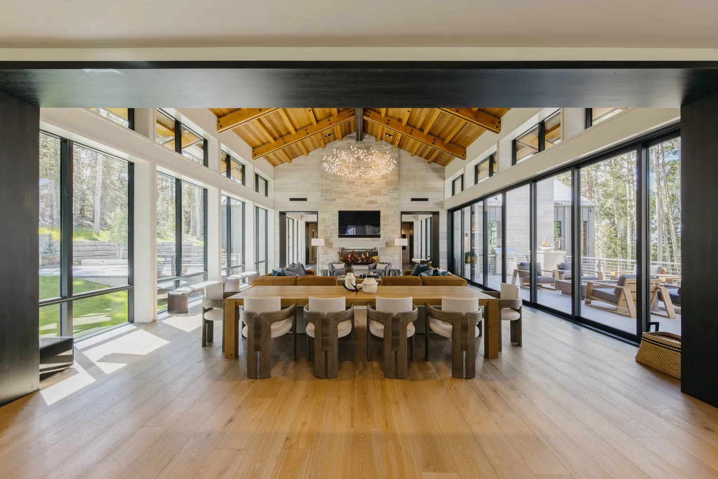 A spacious dining and living area with large windows and a high wooden ceiling.