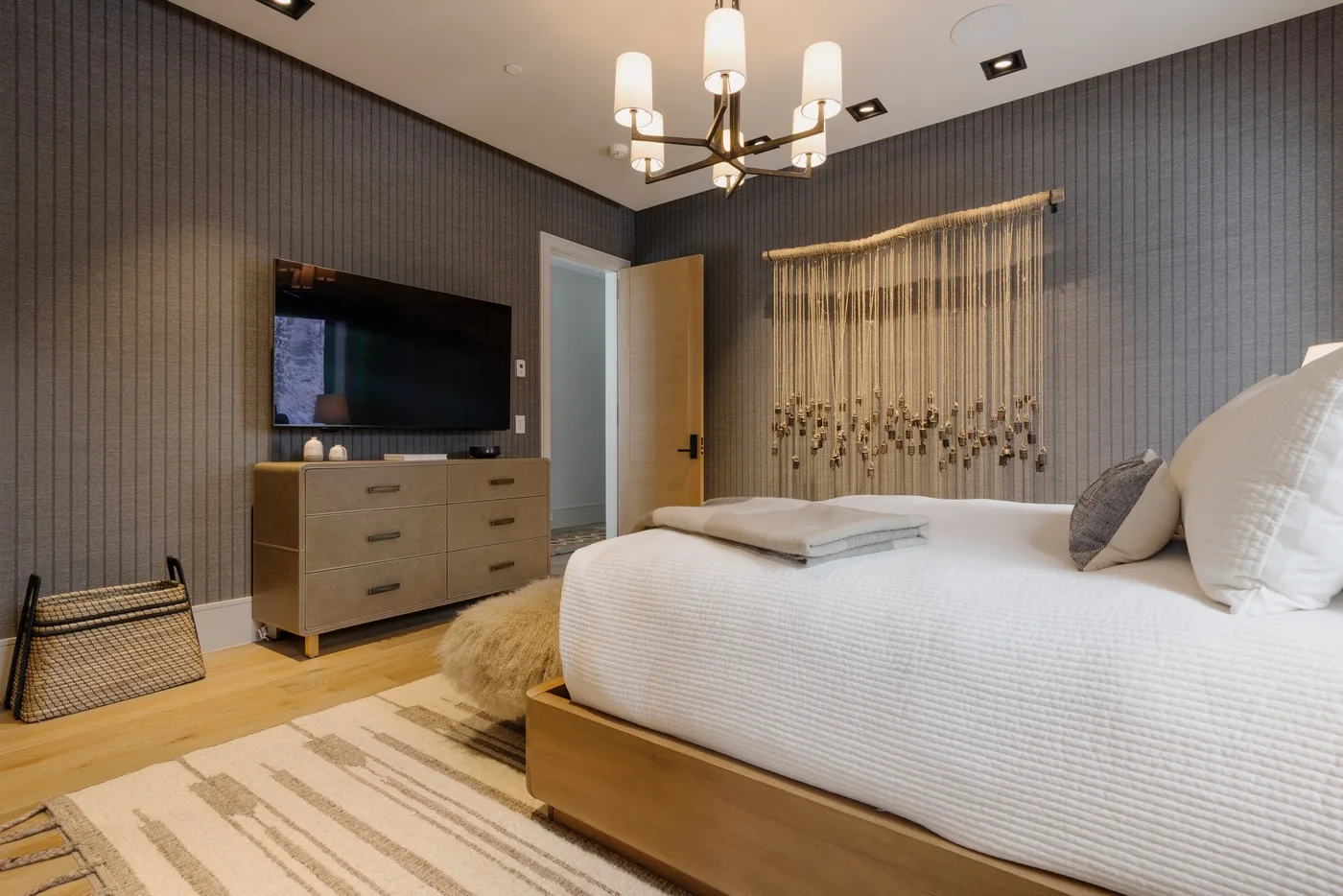 A bedroom with a neatly made bed, a dresser, and a television.