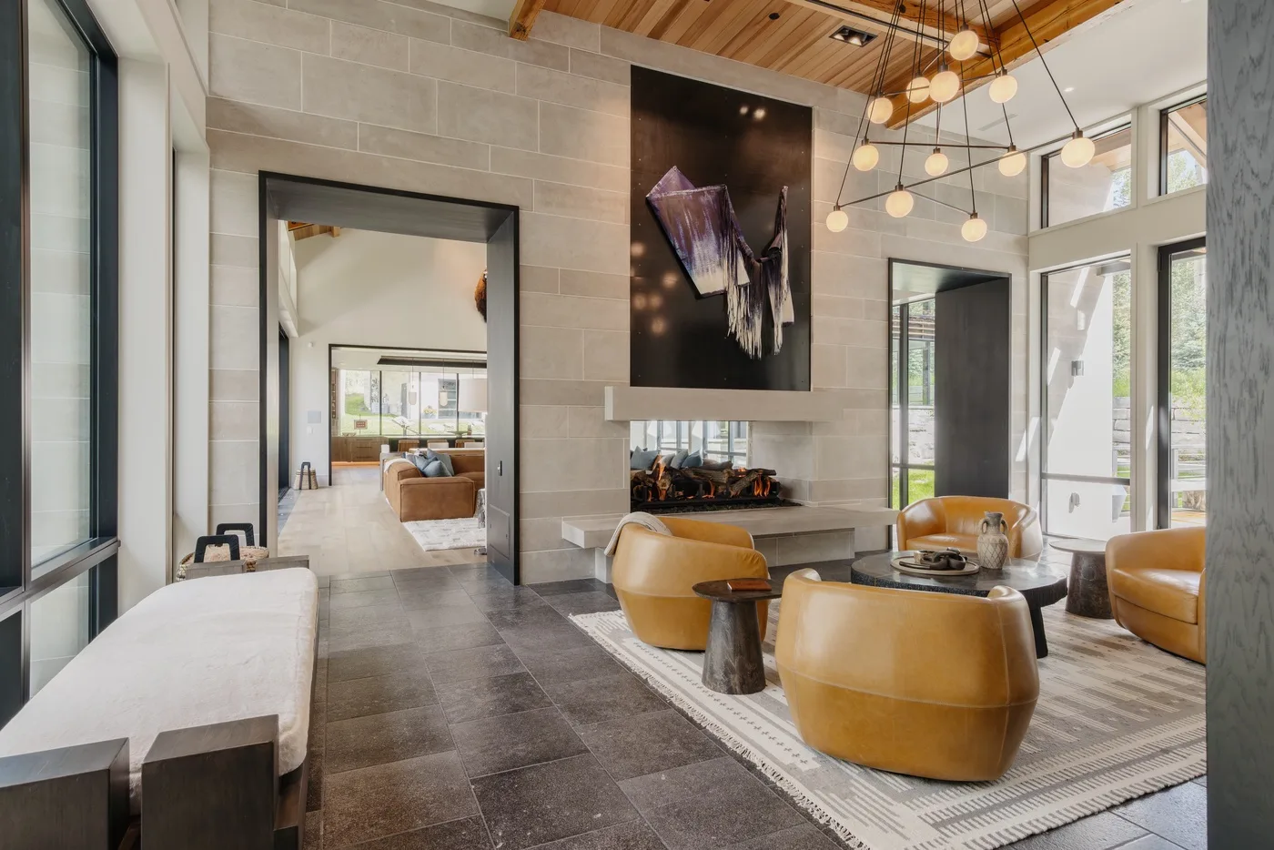 A modern lounge with seating around a low table beneath pendant lights.
