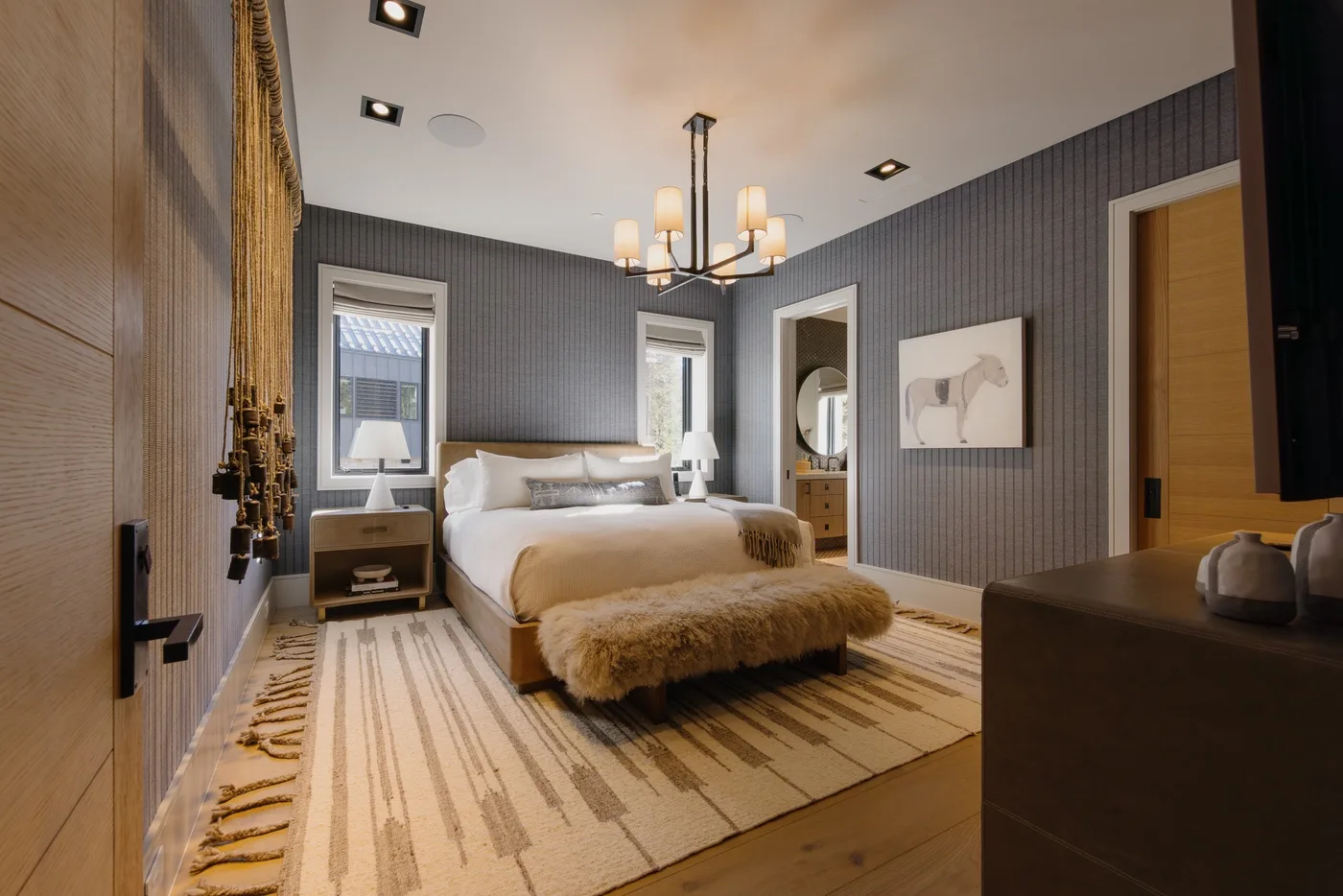 A bedroom with a bed, striped rug, and pendant light.