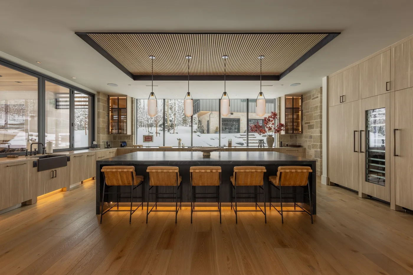 A modern kitchen with a central island and wooden bar stools.
